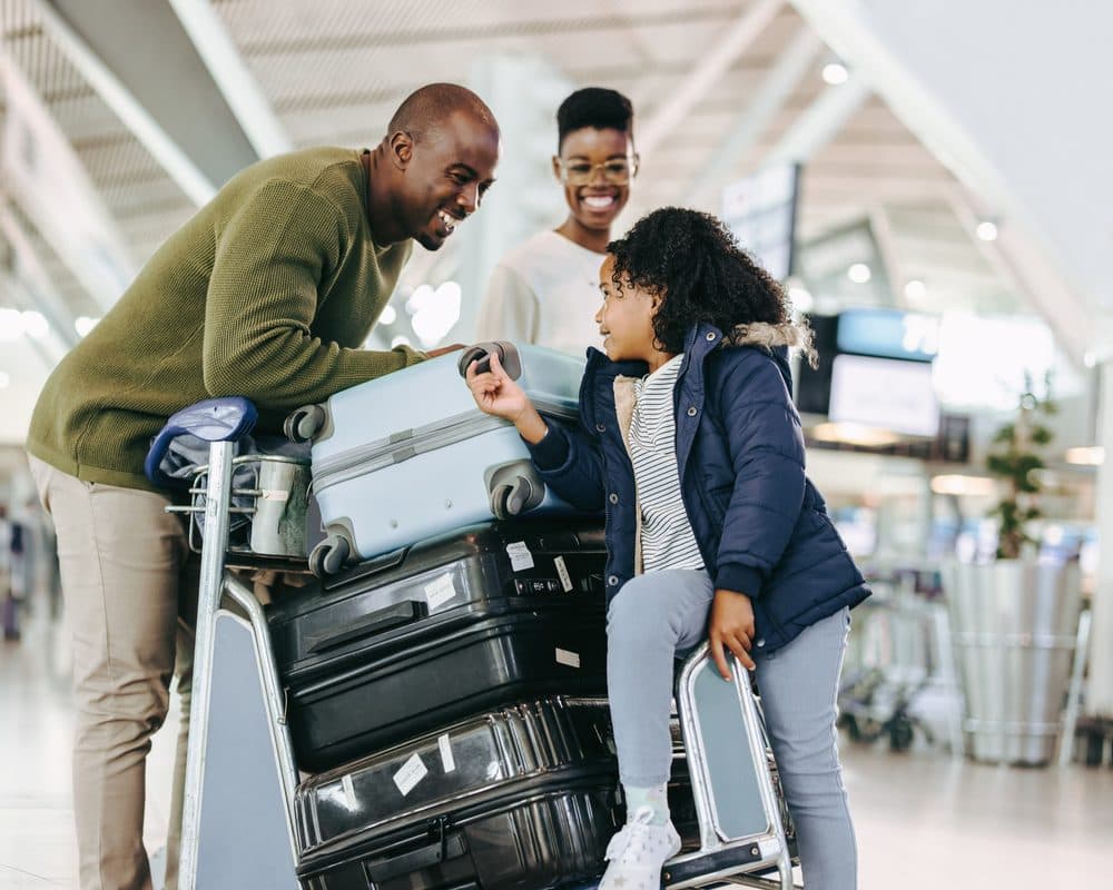 Une famille souriante avec ses valises à l'aéroport